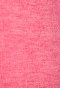 Heldere roze linnen stof met een gestructureerde weving, die een subtiele glans en lichte onregelmatigheden in de oppervlakteconsistentie vertoont.