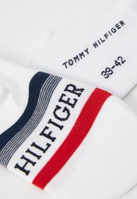 Weiße Socken mit navy-blauen und roten Streifendetails, mit "HILFIGER" in fetten Buchstaben und "TOMMY HILFIGER" Etikett, Größe 38-42. Hergestellt aus einem Baumwoll-Mix.