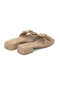 Sandales à glisser en daim beige avec un bout carré et un petit talon bloc, présentant un accent floral avec un détail décoratif en gemmes.