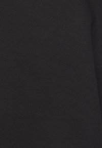 Gros plan sur une texture de tissu noir uni avec un motif de tricot fin, montrant une surface de matériau lisse et uniforme.