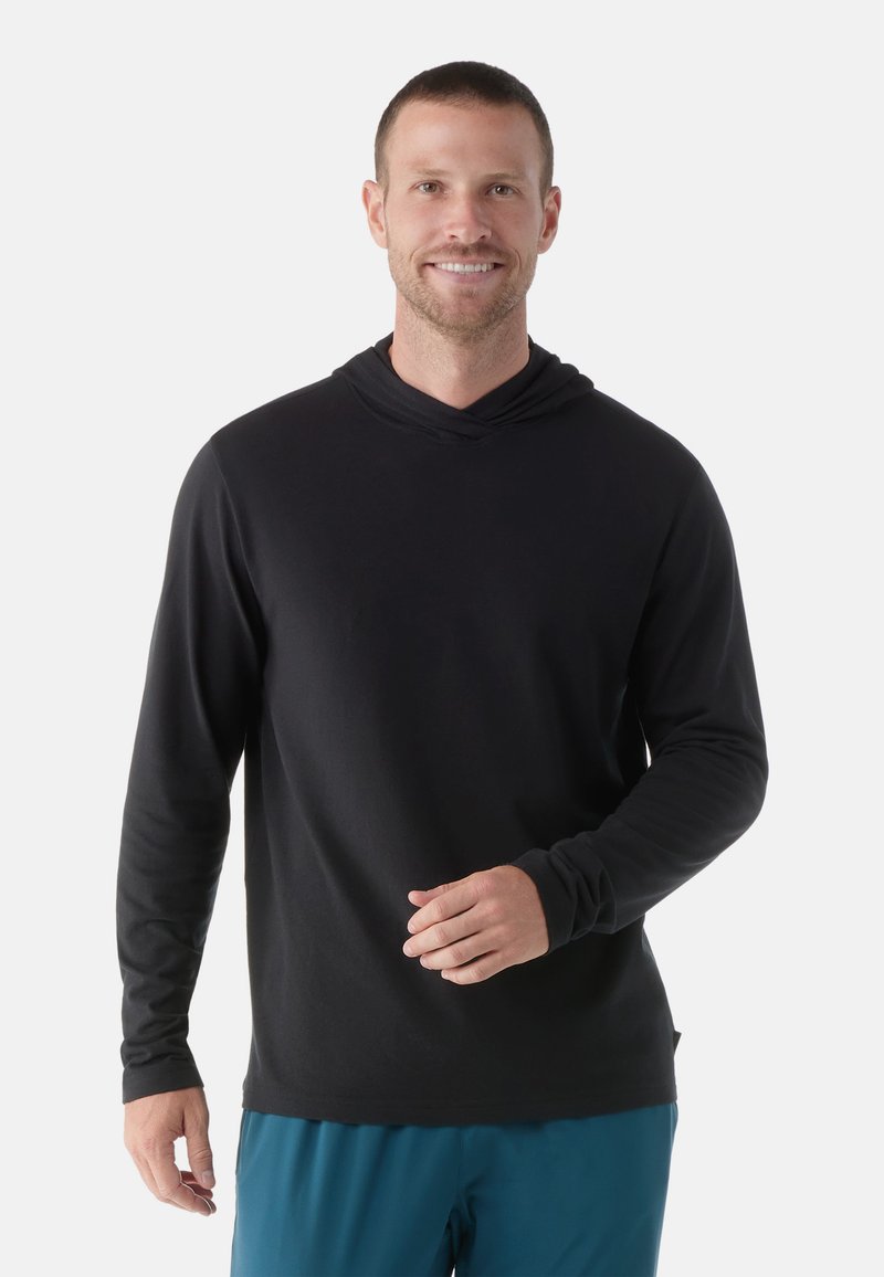 Schwarzer Langarm-Hoodie mit lockerer Passform, aus weichem Stoff, mit doppellagiger Kapuze und nahtlosen Bündchen, getragen mit blauen Shorts.