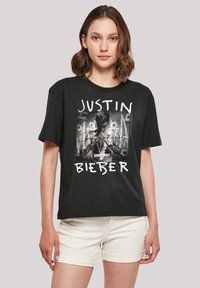 Black cotton t-shirt featuring a graphic of a male figure, with "JUSTIN BIEBER" printed in white around a black-and-white design.