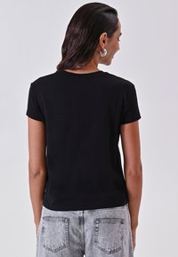 Zwarte T-shirt met korte mouwen en een klassieke ronde hals, soepel materiaal en een getailleerde pasvorm. De achterzijde toont een eenvoudige stijl, zonder grafische elementen.