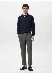 Navy zip-up sweater made of soft fabric, paired with gray tailored trousers. The outfit features a collared shirt and black leather shoes.