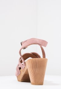 Rosa Wildleder-Absatzsandale mit mehreren überkreuzten Riemen, einem Holzblockabsatz und einem verstellbaren Knöchelriemen.