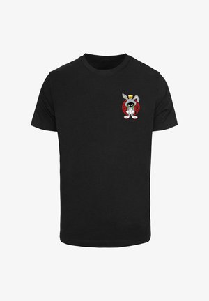 Musta puuvillapaita, jossa on pieni graafinen kuva sarjakuvajäniksestä hatussa punaisella ympyrätaustalla ja valkoisilla yksityiskohdilla alareunassa.