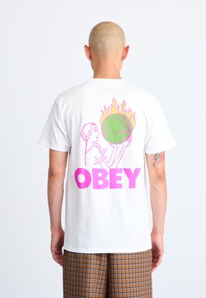White cotton T-shirt featuring a graphic design on the back. The design includes a pink "OBEY" text, flames, and a green globe held by a figure.