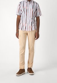 Gestreept T-shirt met korte mouwen in wit, roze en zwart, gecombineerd met lichtbeige cargobroek met zijzakken en bruine sneakers.