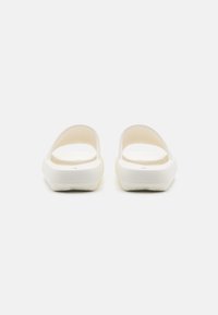 White open-back sandals with a smooth rubber texture, wide straps, and a cushioned footbed. Rounded toe and flat sole design.