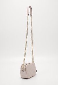 Prošívaná světle růžová kabelka přes rameno s dvojitým zipem, zlatým řetízkovým popruhem a strukturovaným obdélníkovým tvarem. Hladký povrch, minimální detaily.