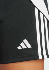 Pantaloni scurți sport negri cu design cu trei dungi albe, având un logo Adidas brodat alb. Material neted, cu o croială ajustată.