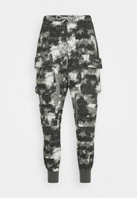 Cargo-byxor i svart, grått och vitt camouflage-mönster. Har flera sidofickor och elastiska muddar vid anklarna. Mjukt tyg.