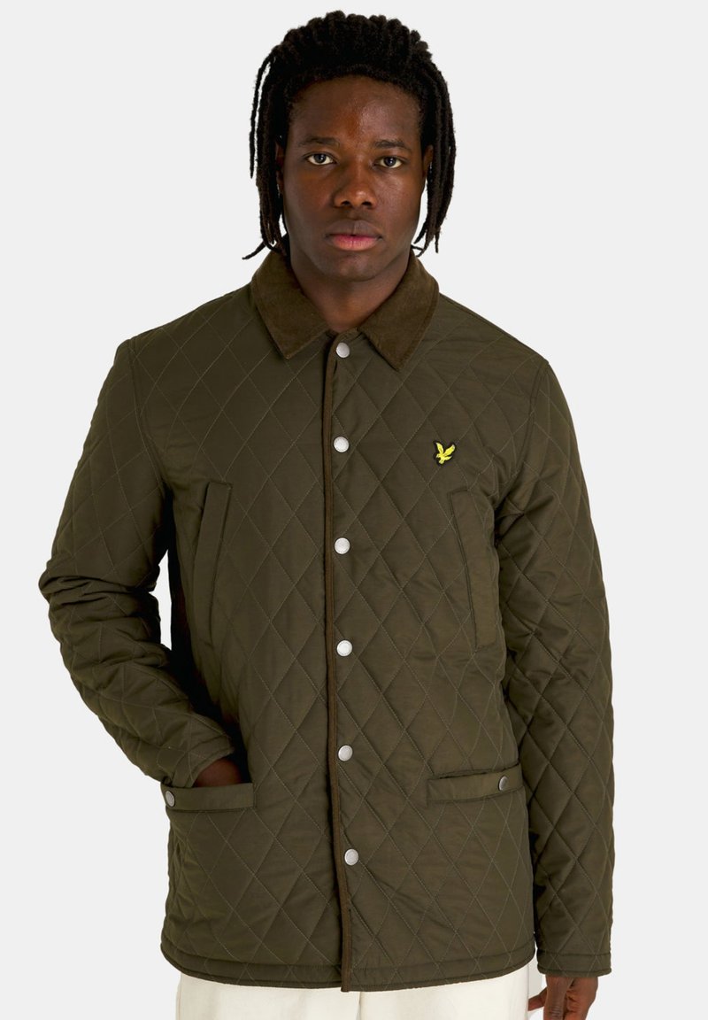 Groene gequiltte jas met een bruine corduroy kraag, voorzien van drukknoopsluitingen, zijzakken en een klein geborduurd logo op de borst.