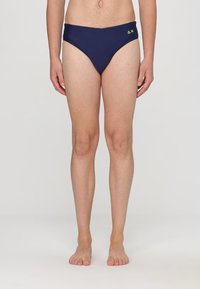 Costumi da bagno blu navy realizzati in materiale elasticizzato, dotati di un taglio a vita bassa con un piccolo logo in verde neon sul lato sinistro.