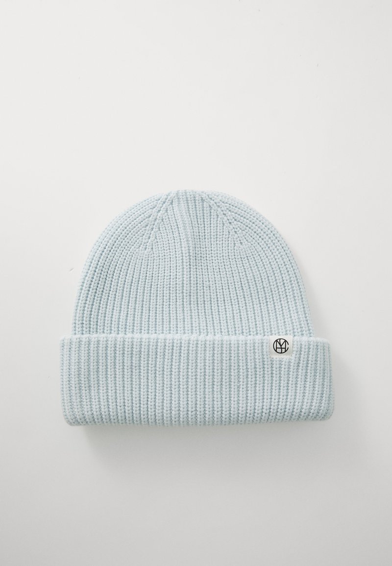 Bonnet en tricot bleu clair avec une texture côtelée et un revers. Présente une petite étiquette de logo noire sur le côté. Tissu doux et coupe ajustée.