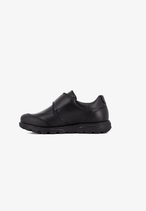 Zapatos negros de piel tipo slip-on con punta redondeada, parte delantera texturizada y suela de goma flexible. Presenta acentos cosidos y detalles de diseño mínimos.