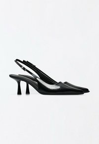 Paire d'escarpins noirs en cuir à bride arrière, talons hauts, bouts pointus et petites boucles sur fond blanc uni.
