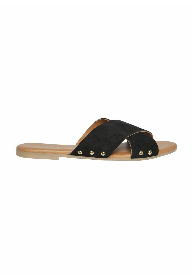 Zwarte suède slide sandaal met gekruiste banden, goudkleurige studs en een lichtbruine voetbed. Plat zoolontwerp, minimalistische stijl.