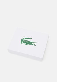 White rectangular box featuring a green crocodile logo with geometric accents. Textured surface and flat design without additional decorations.