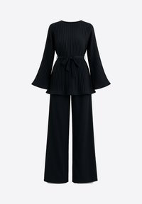 Haut noir plissé avec manches évasées et ceinture nouée, associé à un pantalon noir à jambes larges, créant une tenue coordonnée.