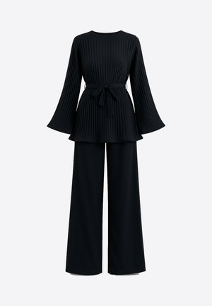 Top negro plisado con mangas acampanadas y cintura anudada, combinado con pantalones negros de pierna ancha, creando un conjunto coordinado.