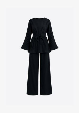Haut noir plissé avec manches évasées et ceinture nouée, associé à un pantalon noir à jambes larges, créant une tenue coordonnée.