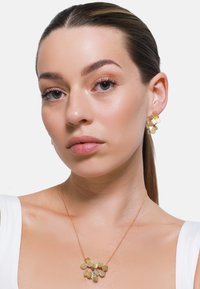 Gouden sieradenset met ronde, gestructureerde oorbellen en een bijpassende ketting met meerdere ronde, platte hangers aan een slanke ketting.