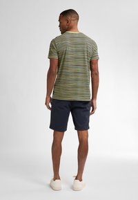 Pruhované tričko v zelené a žluté barvě, které je skombinováno s námořnickými šortkami. Tkanina vypadá měkce, nabízí pohodlný střih s kulatým výstřihem.