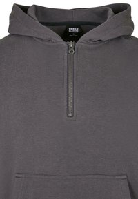 Felpa grigia realizzata in materiale morbido, con zip frontale a metà, grande tasca a marsupio e cappuccio con cordino. Etichetta: Urban Classics.