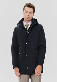 Granatowa kurtka parka z odczepianym kapturem, dwoma przednimi kieszeniami i zapięciem na napy. Gładki materiał o subtelnym połysku i minimalistycznym designie.