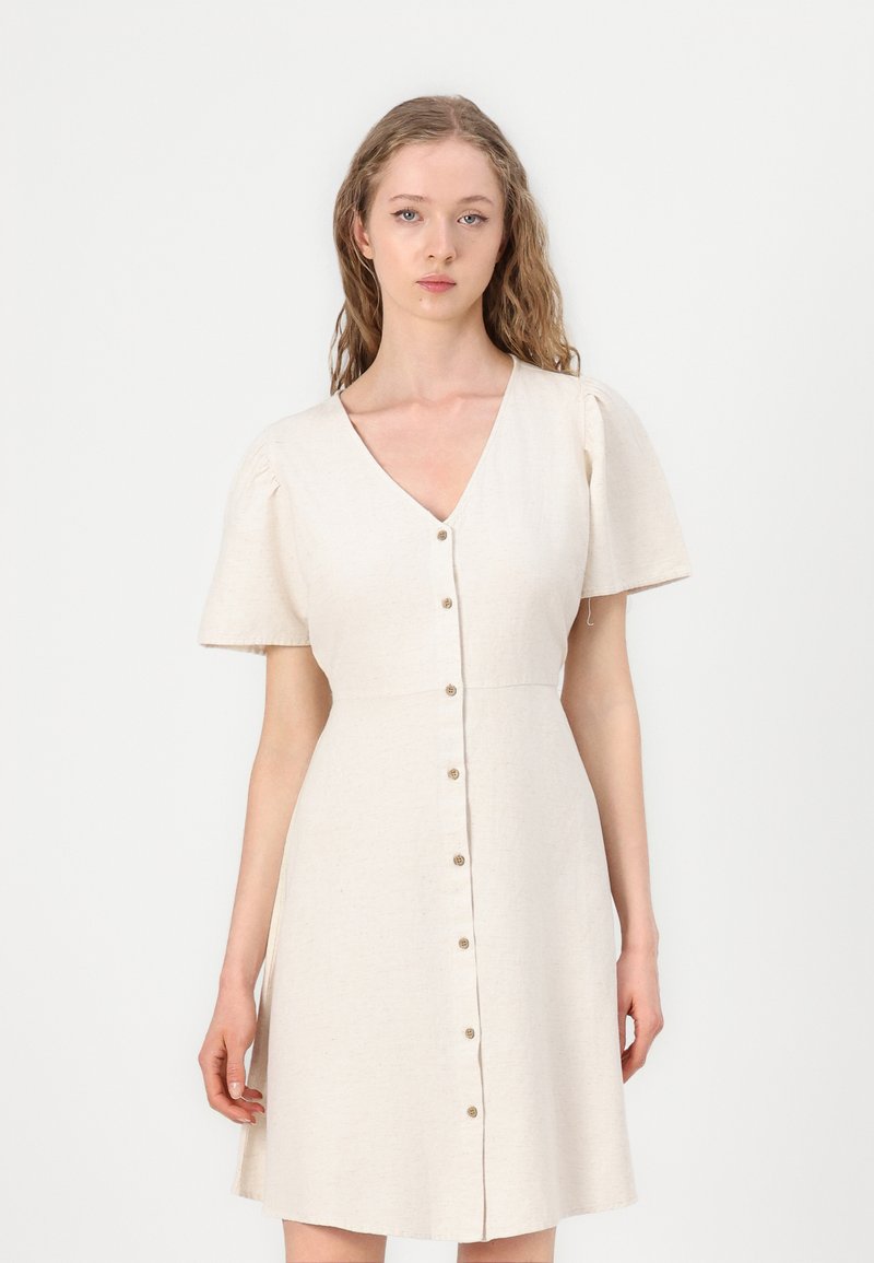 Beige linnen jurk met korte poffende mouwen, V-hals en knoopsluiting aan de voorkant. A-lijn vorm met een textuurfinish.