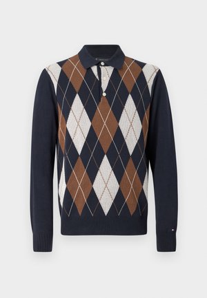 Pletiva poliester s mornarskim tijelom i smešnim, belim i krem argyle uzorkom; ovratnik sa tri dugmeta i rebrasti manžeti.