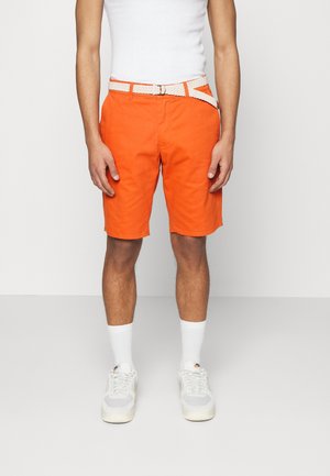 Orangene Shorts aus Baumwolle mit einem gewebten weißen Gürtel. Kombiniert mit weißen knielangen Socken und grauen Sneakers. Gerade geschnittenes Design.