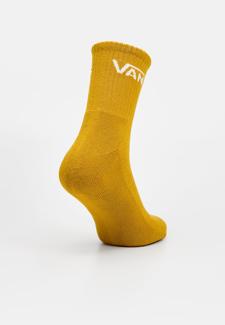 Calzino alla caviglia giallo senape con logo bianco "VANS" sul risvolto, esposto su una forma a piedi su uno sfondo bianco uniforme.
