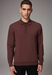 Burgundy hosszú ujjú pólóing sima anyagból; galléros nyakkal és három fekete gomb részlettel rendelkezik. Szegélyezett mandzsetták és dér.