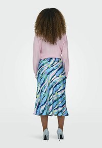 Vaaleanpunainen pitkähihaisruutupaita, joka on yhdistetty hulmuavaan moniväriseen hameeseen, jossa on sinisiä, vihreitä ja vaaleanpunaisia abstrakteja aaltoja.