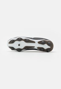 Suola di scarpini da calcio in bianco e nero con tacchetti in gomma, caratterizzata da un design testurizzato e un logo ben visibile sul tallone.