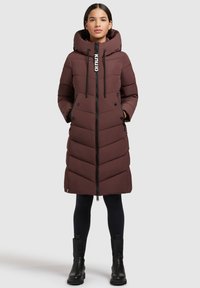 Dlouhá hnědá péřová bunda s kapucí, která má zipové zapínání, vzor v kosočtverci, dvě boční kapsy a šňůrkové detaily.