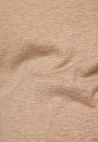 Beige strukturiertes Gewebe mit einem weichen, leicht dehnbaren Gewebe, das subtile Farbvariationen und eine glatte Oberfläche aufweist.