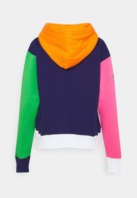 Mikina s kapucí s designem v barevných blocích, obsahující oranžové, zelené, růžové, fialové a bílé části. Vyrobena z měkké tkaniny.