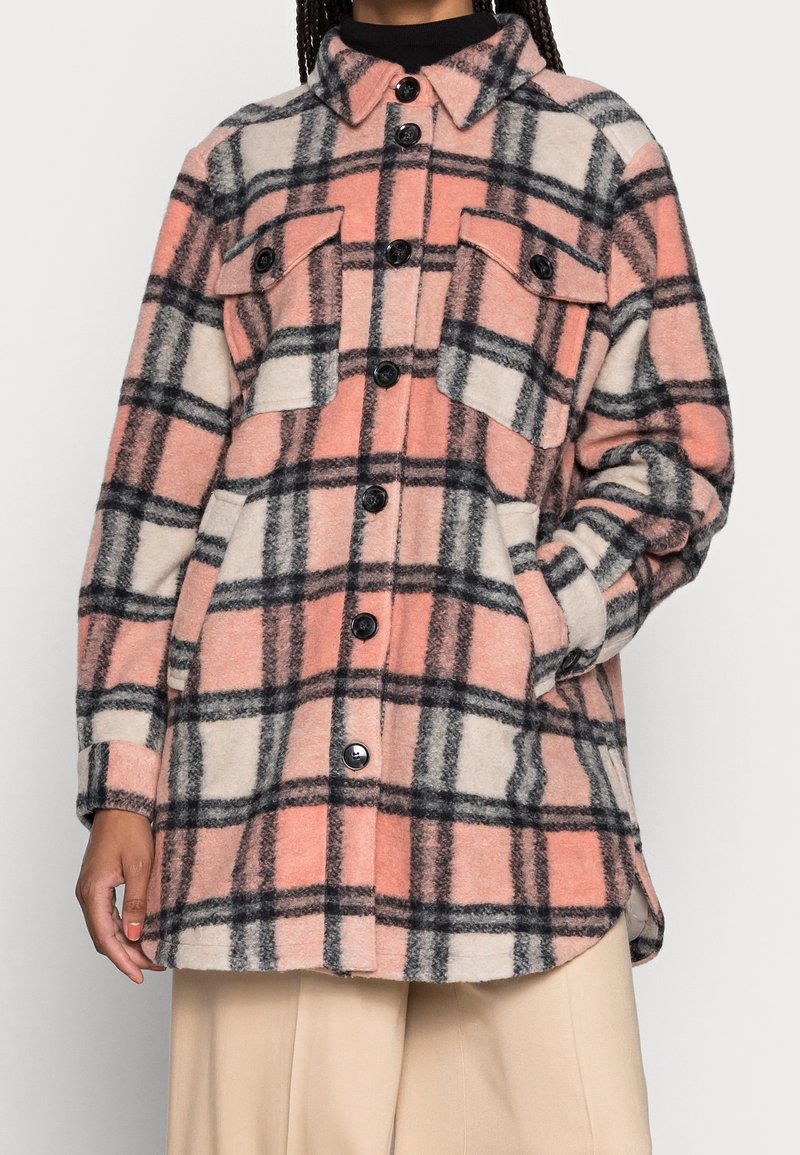 Kostkovaná flanelová košile v jemné růžové, krémové a černé barvě, s knoflíkovým zapínáním, dvěma náprsními kapsami a uvolněným střihem.