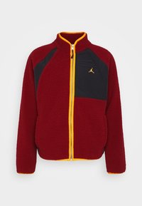 Rote Fleecejacke mit schwarzen Einsätzen und gelben Akzenten. Verfügt über einen hohen Kragen, einen durchgehenden Reißverschluss und ein Logo auf der Brust. Weicher Stoff.