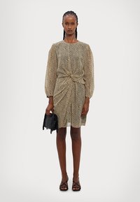 Šaty s krátkymi rukávmi z ľahkej, priesvitnej tkaniny, s béžovým podkladom a čiernym zvieracím vzorom, s detaily uzla v oblasti pásu a jemným drapovaním.