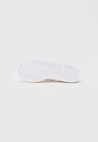 Sola de um sneaker branco com padrão de piso em espinha de peixe, textura de borracha suave, forma arredondada e um design plano para maior aderência e estabilidade.