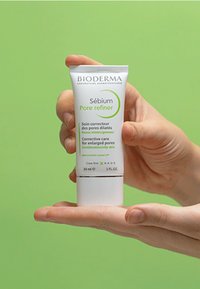 Crema Bioderma Sébium Pore Refiner in tubo bianco da 30 ml. Presenta testo verde, tappo a scatto, tenuta contro uno sfondo verde chiaro uniforme.
