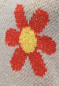 Țesătură tricotată cu un design mare de floare roșie având un centru galben, pe un fundal gri cu cusături texturate și pete subtile.