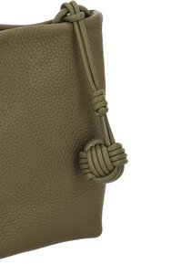 Kožená taška olivově zelené barvy s texturovaným povrchem, zdobená uzlovým detailem na popruhu a zúženým tvarem.
