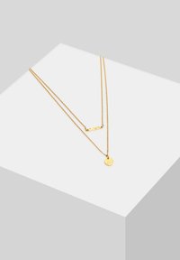 Goldschichtige Halskette mit einem strukturierten Balken und einem kleinen runden Anhänger, beide auf dünnen Ketten mit einem sauberen Finish.