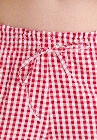 Bermuda a quadretti rossi e bianchi con vita elasticizzata, dotate di un laccetto regolabile nella parte frontale. Realizzate in un tessuto leggero e traspirante.