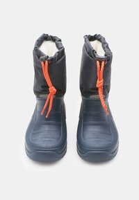 Morske vodoodporne čevlji z mehkim belim podloženjem, vrvica na vrhu v oranžni barvi, teksturiran podplat in gladka zunanja zasnova.